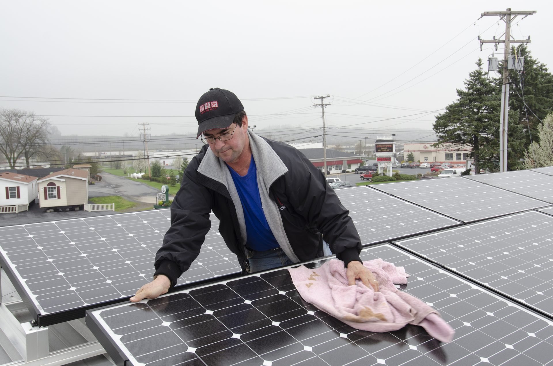 Person cleaning solar panels with a soft brush and water