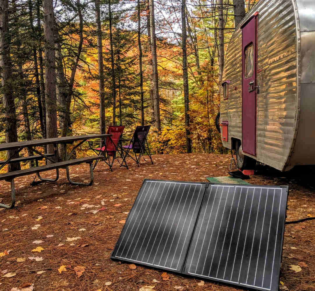 Portable suitcase solar panel set up beside a travel trailer
